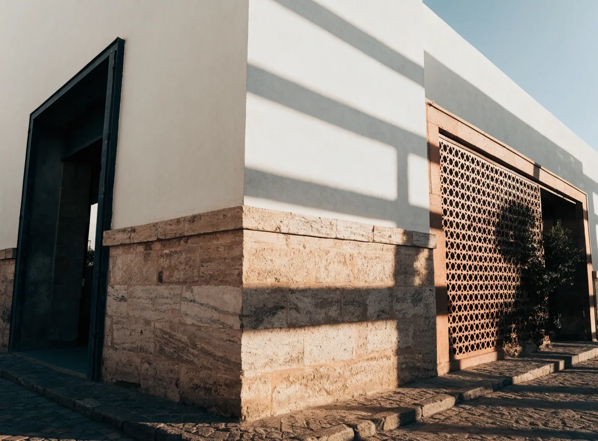 Low-angle view of the museum exterior at late afternoon, with marble and brick reading in two stepped planes of light